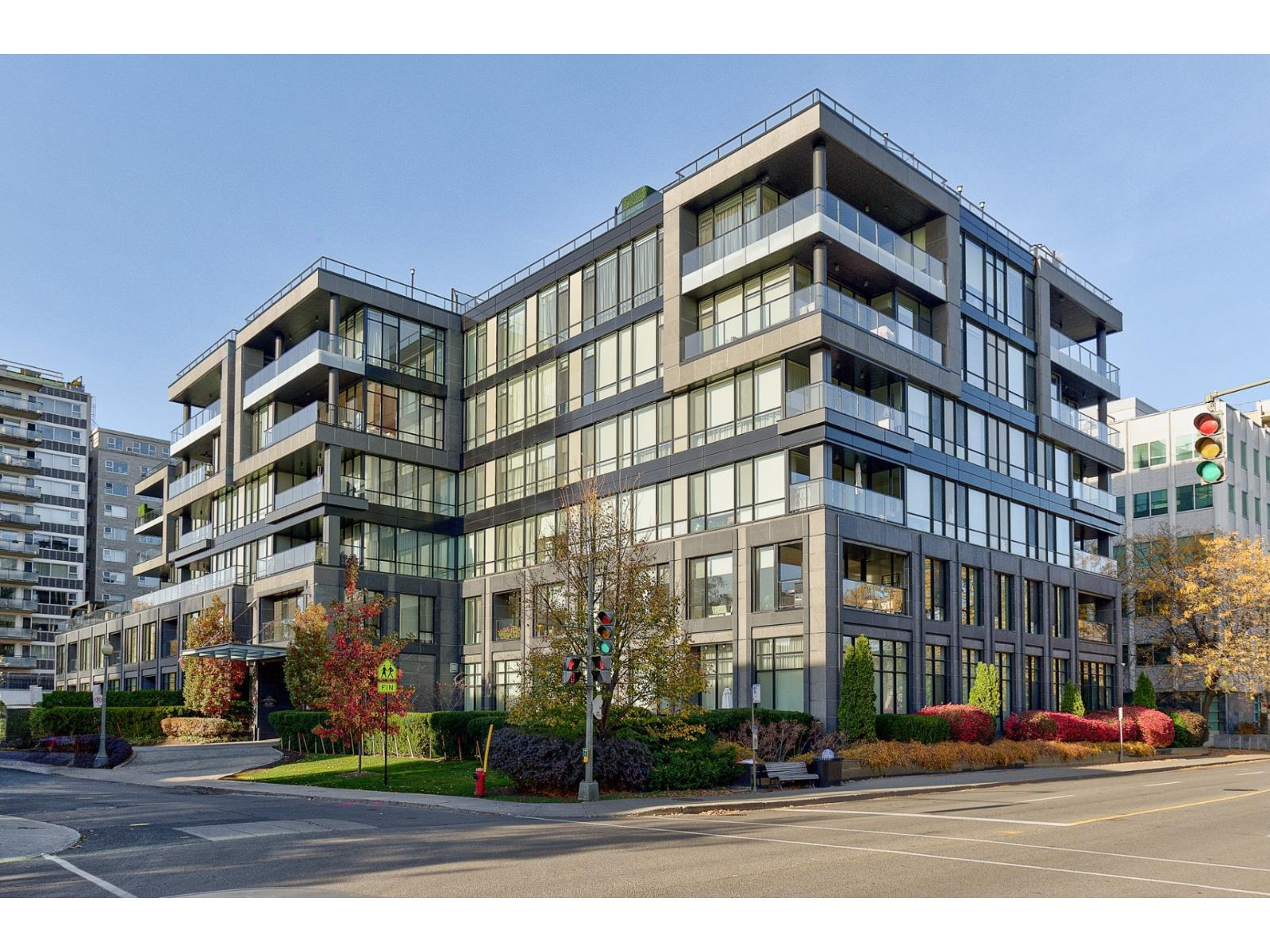 Modern mid-rise residential building with glass balconies at a city intersection